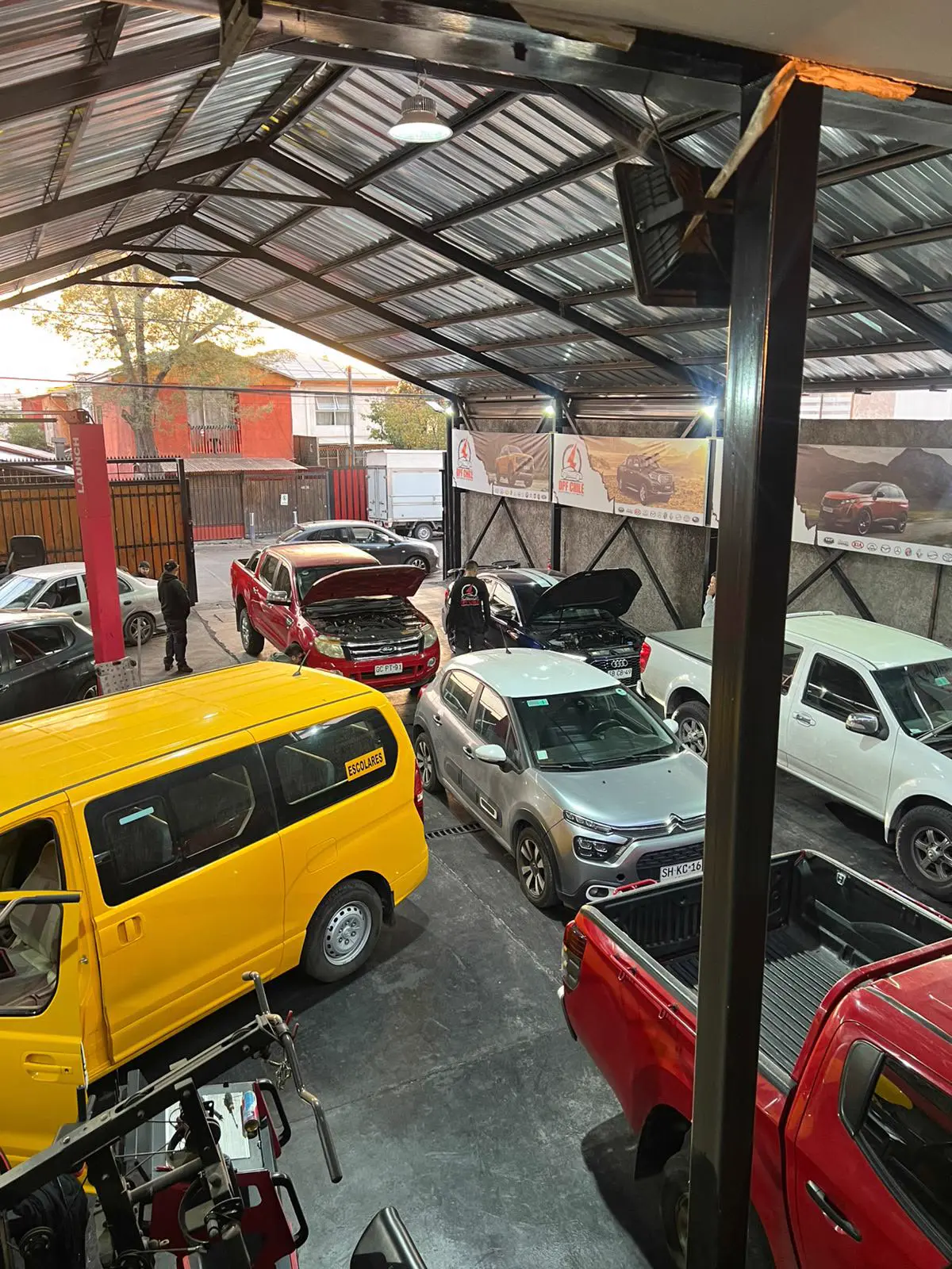 Nave técnica industrial con múltiples bahías de trabajo activas, elevadores y fosa de inspección.
